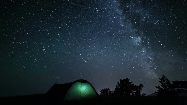 Rotating milky way above tent at night time lapse