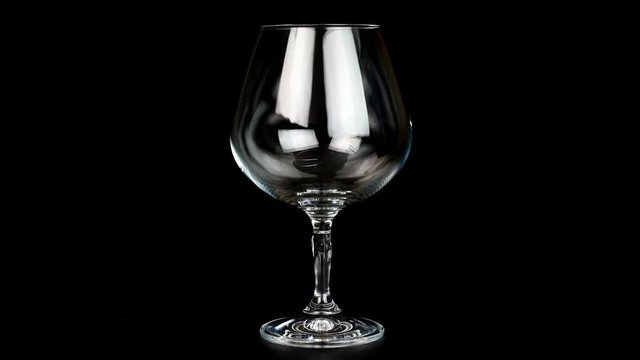 Close up of brandy being poured into snifter on black background