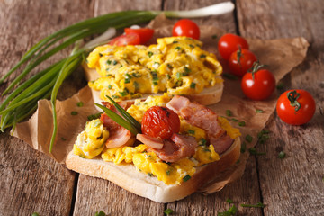 sandwiches with fried eggs, bacon and tomatoes close-up on the table. horizontal
