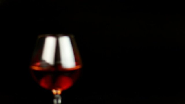 Man take a glass with brandy over black background