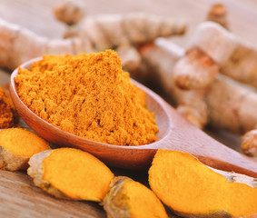 Turmeric and turmeric powder on wooden background