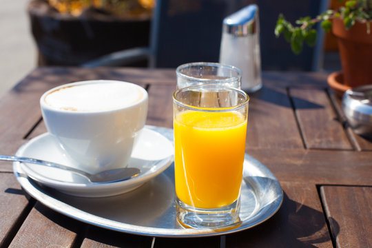 Bottle of Freshly squeezed orange juice sitting on a rustic wooden table.