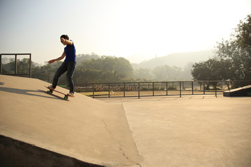 Obraz premium skateboarding woman riding skateboard at skatepark ramp
