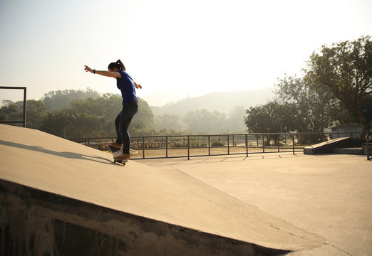 skateboarding woman riding skateboard at skatepark ramp