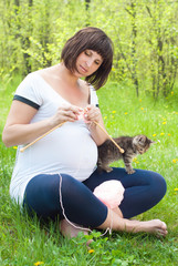 Pregnant Woman with Kitten knitting in the Park. Family Concept.