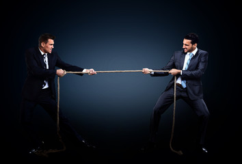 Two business men pulling rope in a competition