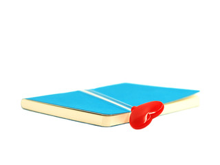 Red heart on the blue open book isolated on white background, select focus.
