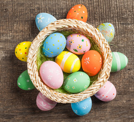 Easter eggs in nest on color wooden background