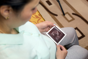 Pregnant woman looking at ultrasound photo.