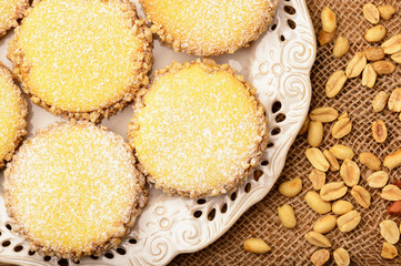 Butter cookies (alfajores) with caramel and peanut on wooden background.