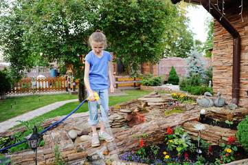 Aadorable brunette kid girl, watering the plants