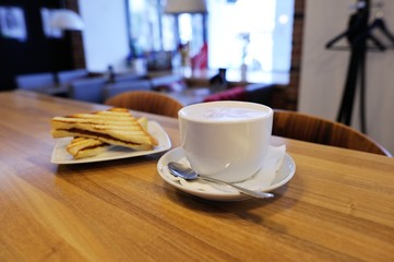Cup of cappuccino with blur coffee shop background