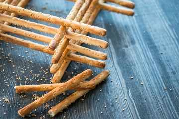Bunch of homemade grissini breadsticks in a glass jar on wooden surface