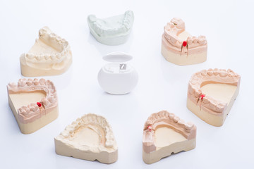 Teeth molds with dental floss on a bright white table