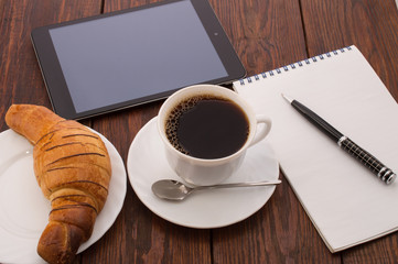breakfast with cup of black coffee, croissants and notebook