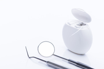 Dental floss with basic dental tools on a white table