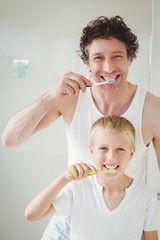 Portrait of father and son brushing teeth