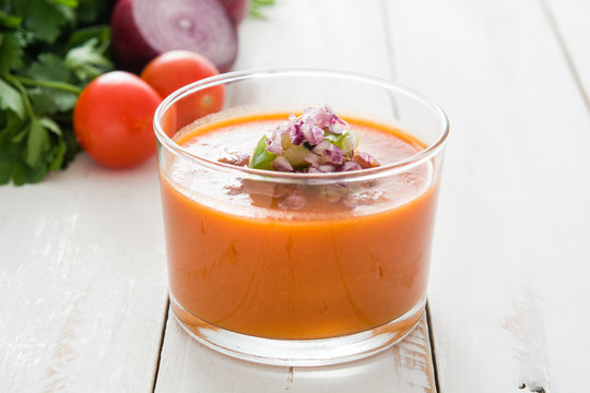 Gazpacho soup and ingredients on white wooden background
