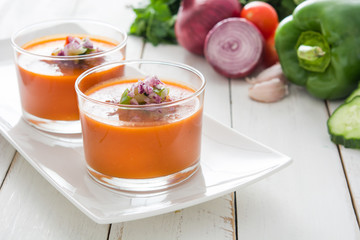 Gazpacho soup and ingredients on white wooden background
