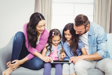 Family looking in tablet computer while sitting on sofa