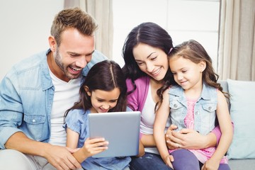 Family smiling while looking in digital tablet