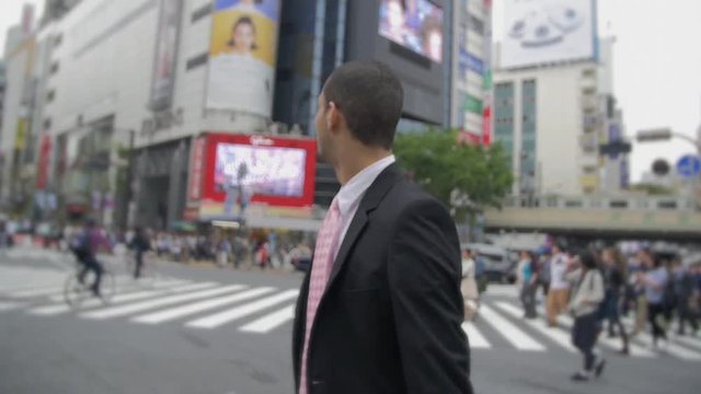 Confident young mix race business man walking Hachiko Exit Shibuya crossing Japan. 