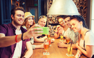 happy friends with smartphone taking selfie at bar