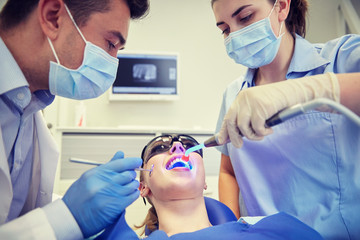 dentists treating woman patient teeth at clinic