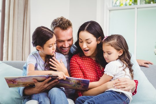 Family looking in picture book while sitting on sofa