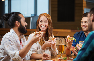 friends eating pizza with beer at restaurant