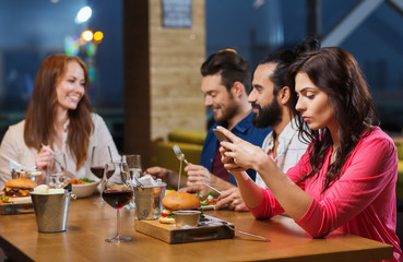 woman with smartphone and friends at restaurant