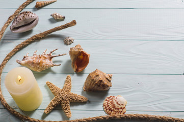 Blue wooden background with seashells, starfish and a burning candle. Concept of the summer time...