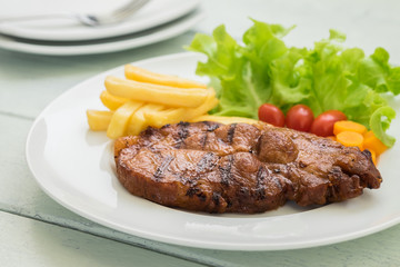 Grilled steak with french fries and vegetables on plate