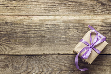 Background with gift box with purple ribbon on wood grunge board