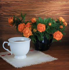 still life with flowers and cup of tea on a wooden background