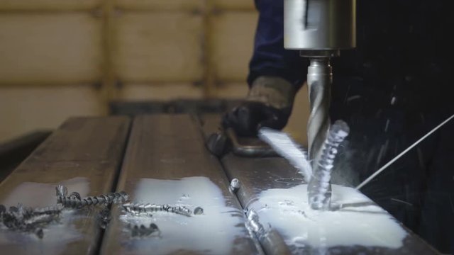 Closer look of the drilling machine making a hole on the metal sheet and some metal scrapes aere coming out from the drilling