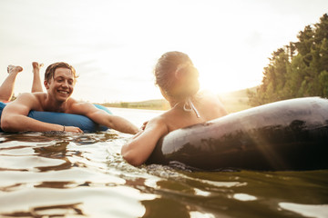 Affectionate young couple floating on inner tubes in lake