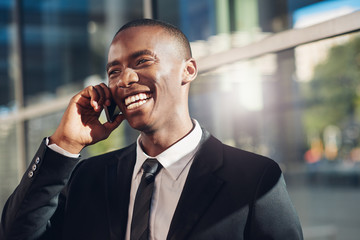Handsome African businessman laughing and talking on his phone