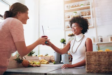 Poster Female bartender serving a glass of fresh juice to customer © Jacob Lund