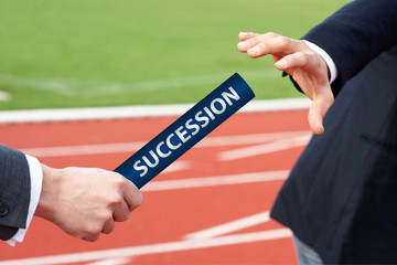 Succession - Businessman hands over baton in stadium at relay race 