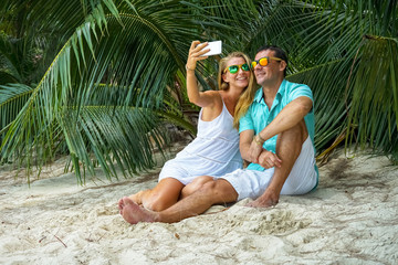 Young couple sitting on a tropical beach is photographed
