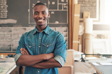 Fototapeta premium Confident young African designer in his studio with arms folded