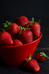 Juicy, fresh strawberries in a dish on a black background