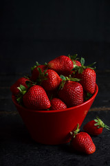 Juicy, fresh strawberries in a dish on a black background