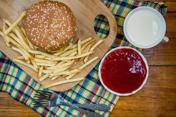 Fast food set big hamburger and french fries on wood background