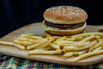 Fast food set big hamburger and french fries on wood background