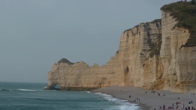Tourist found on the shore of the beach in Etretat and the big cliff on the background