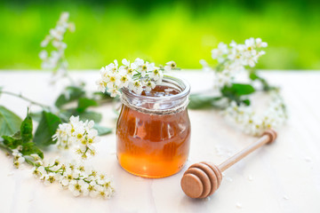Honey and acacia flowers with a wooden dipper on garden background.