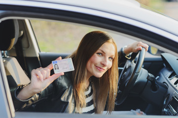 Attractive young woman proudly showing her drivers license - obrazy, fototapety, plakaty