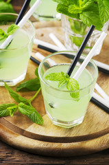 Green sweet cocktail with mint and ice on the wooden table